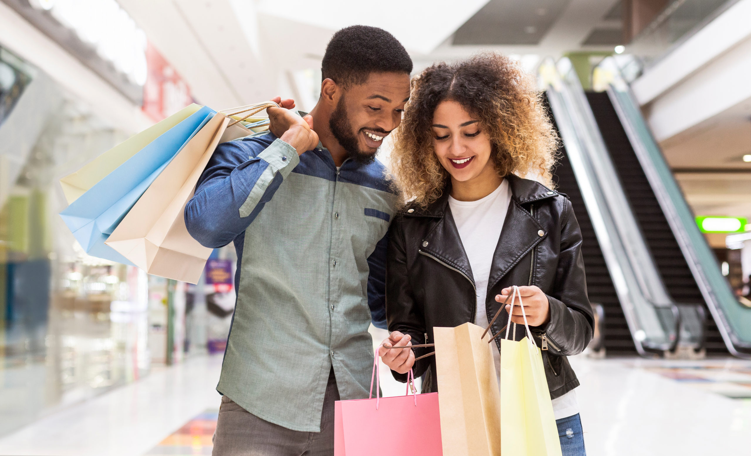 Couple Shopping in Mall stops to look into shopping bags happily