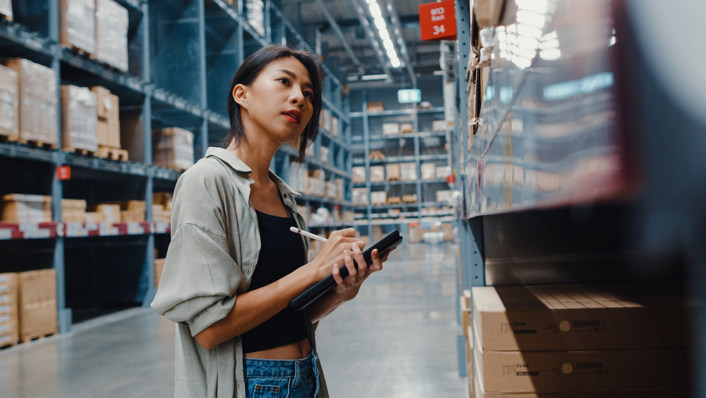 Young woman counts warehouse inventory on iPad
